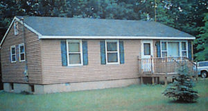 The house in 2015. The first change was the arctic entry on the south to provide a protected entry and capture solar energy. The solar panels were added in 2014 for emergency lighting and backup for the freezers and furnace during power outages. The shrubbery in front of the house changes the microclimate by blocking the wind and highway dust and noise.
